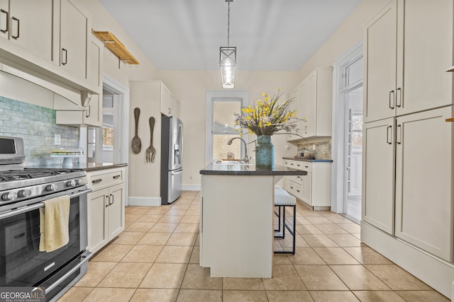 kitchen with a breakfast bar, an island with sink, appliances with stainless steel finishes, and tasteful backsplash