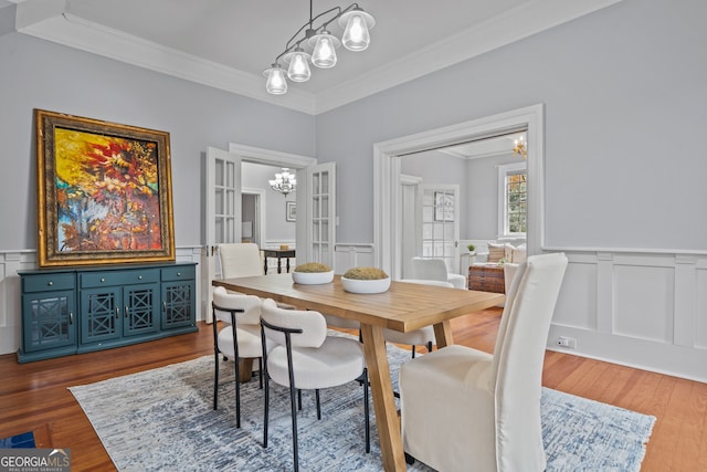 dining room with hardwood / wood-style floors, french doors, ornamental molding, and a notable chandelier