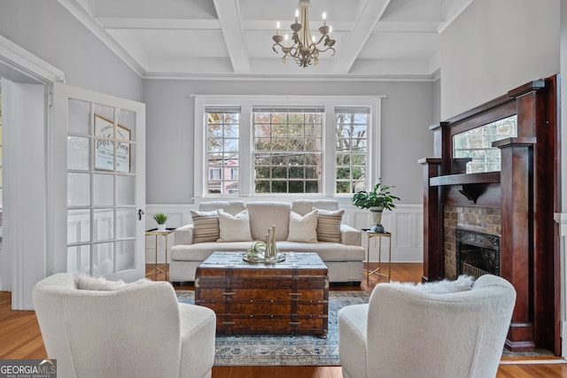 living room featuring beam ceiling, light hardwood / wood-style flooring, a notable chandelier, and coffered ceiling