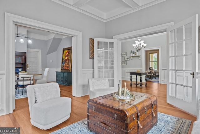 living area featuring coffered ceiling, crown molding, light hardwood / wood-style floors, a notable chandelier, and beam ceiling