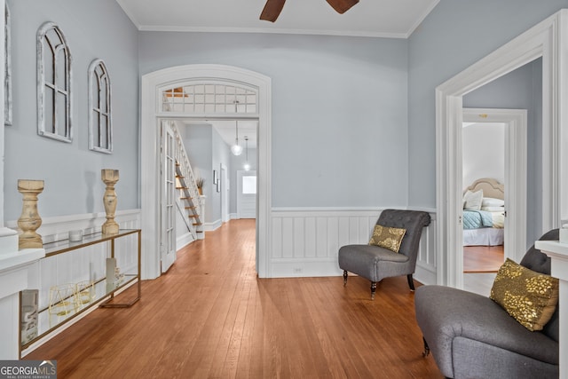 living area featuring ceiling fan, hardwood / wood-style floors, and ornamental molding