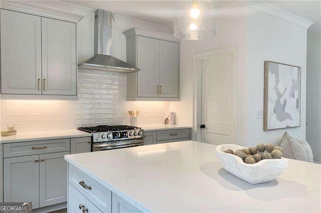 kitchen featuring high end range, light stone countertops, backsplash, wall chimney exhaust hood, and gray cabinets