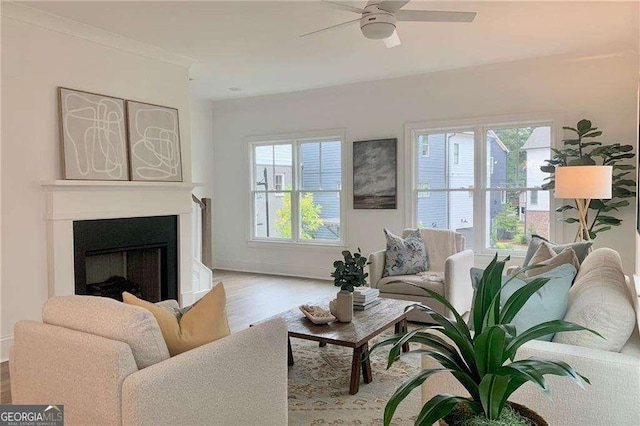 living room with a wealth of natural light, crown molding, ceiling fan, and light wood-type flooring