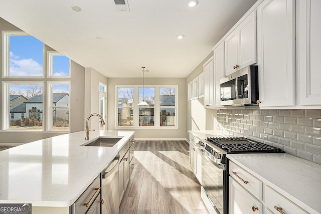 kitchen featuring appliances with stainless steel finishes, white cabinetry, light hardwood / wood-style flooring, and a wealth of natural light