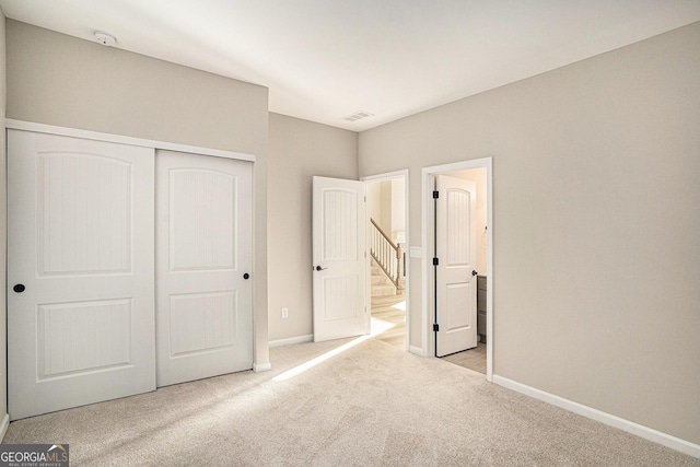 unfurnished bedroom with light colored carpet and a closet