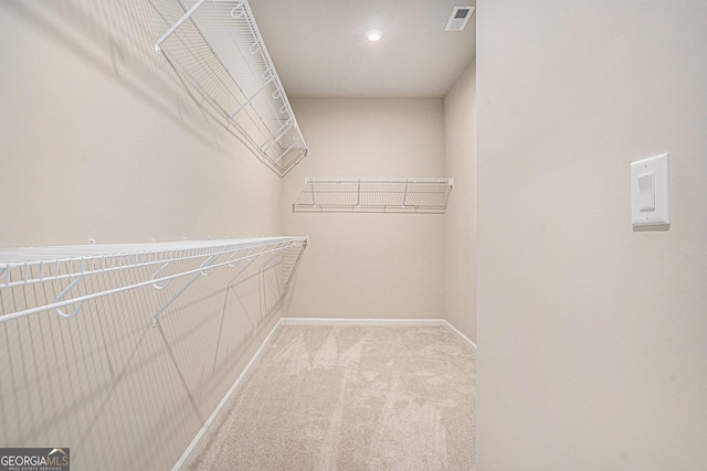 walk in closet with light colored carpet