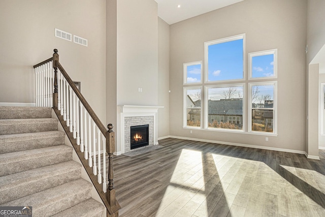 unfurnished living room featuring a high ceiling, dark hardwood / wood-style flooring, and a brick fireplace