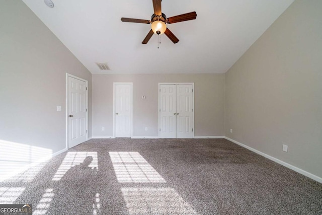 unfurnished bedroom featuring carpet, ceiling fan, lofted ceiling, and multiple closets