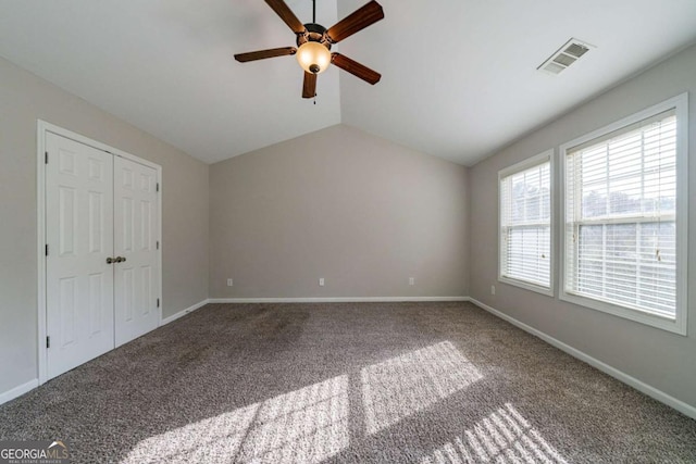 unfurnished bedroom with carpet flooring, ceiling fan, a closet, and vaulted ceiling