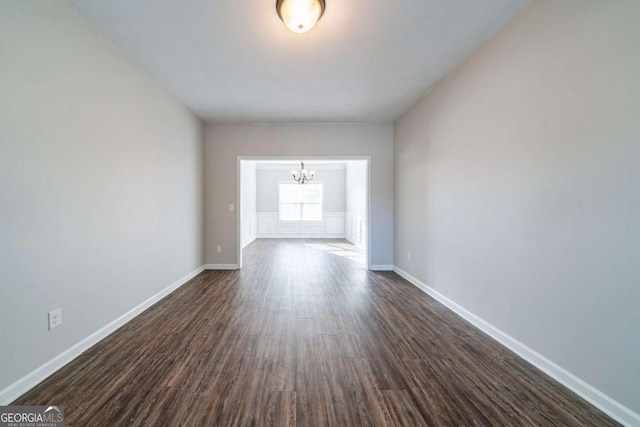 spare room featuring a chandelier and dark hardwood / wood-style flooring