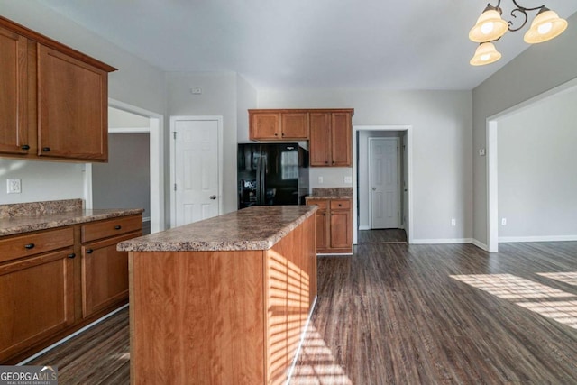 kitchen featuring dark wood-type flooring, hanging light fixtures, black fridge, a notable chandelier, and a kitchen island