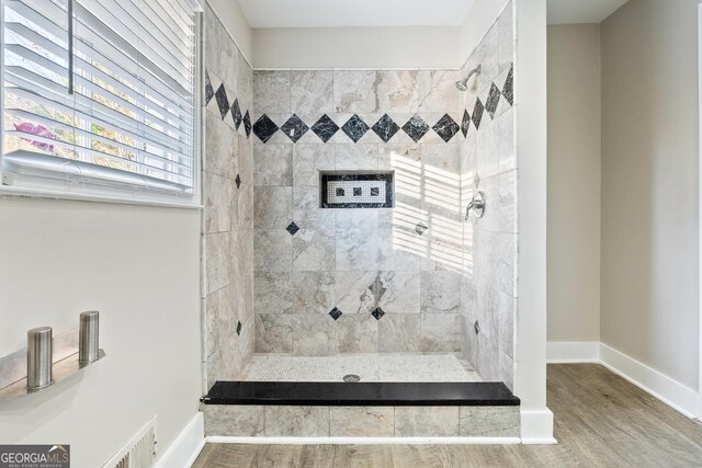 bathroom featuring wood-type flooring and tiled shower