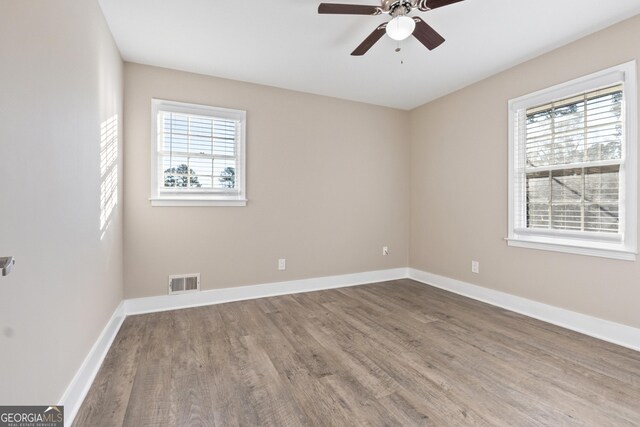 spare room featuring ceiling fan, wood-type flooring, and a wealth of natural light