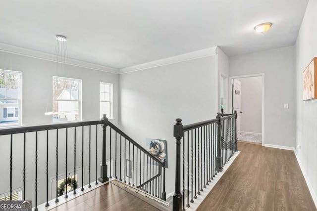 hall with crown molding, baseboards, wood finished floors, and an upstairs landing