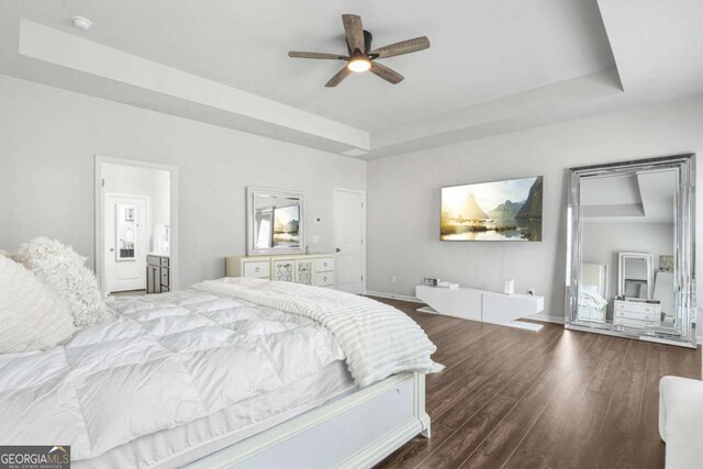 bedroom featuring a raised ceiling, ceiling fan, and dark wood-type flooring