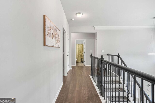 hallway featuring baseboards, wood finished floors, and an upstairs landing