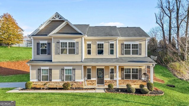 craftsman-style home featuring a front lawn, covered porch, and brick siding