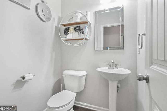 bathroom featuring toilet, baseboards, a sink, and wood finished floors