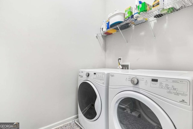 washroom featuring washing machine and dryer, laundry area, and baseboards