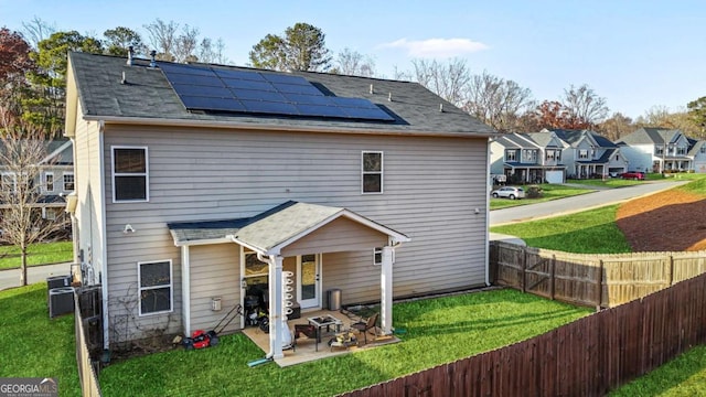 back of property with a yard, solar panels, a patio area, fence, and a residential view