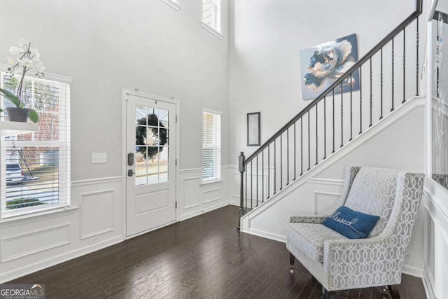 entrance foyer with hardwood / wood-style floors, wainscoting, a wealth of natural light, and stairway
