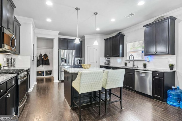 kitchen with tasteful backsplash, a sink, appliances with stainless steel finishes, light stone countertops, and visible vents