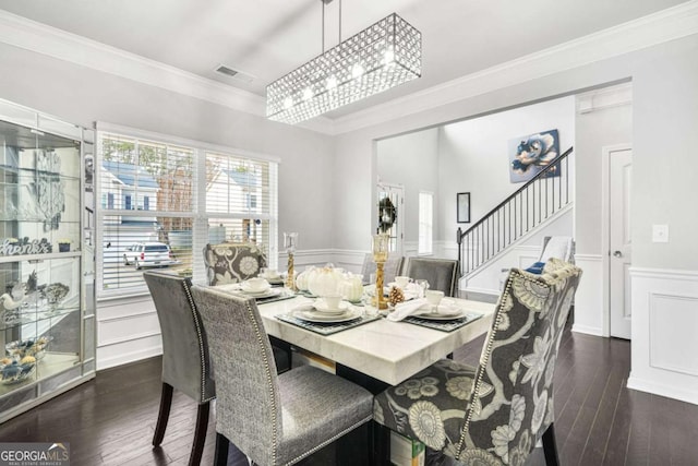 dining area featuring ornamental molding, dark wood-style flooring, wainscoting, and stairway