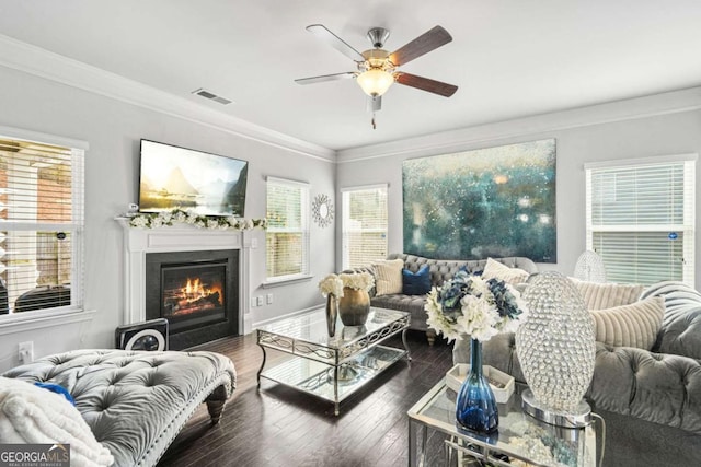 living room featuring ceiling fan, a healthy amount of sunlight, a glass covered fireplace, and visible vents