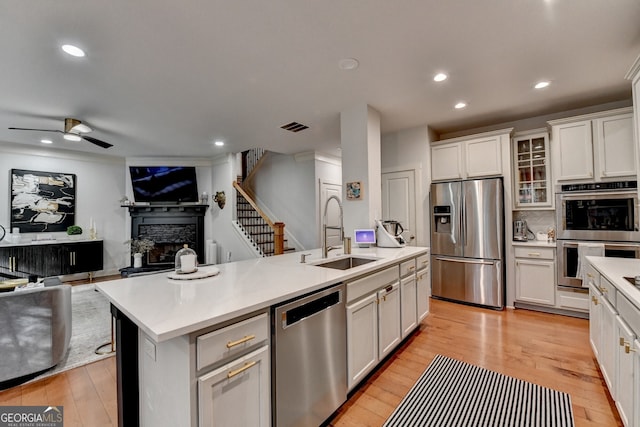 kitchen featuring stainless steel appliances, a kitchen island with sink, sink, white cabinets, and light hardwood / wood-style floors