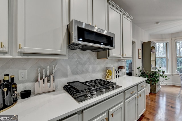 kitchen with light wood-type flooring, backsplash, and gas cooktop