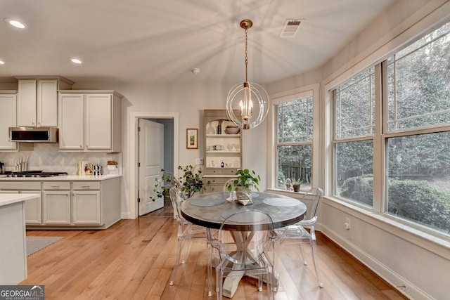 dining space featuring a wealth of natural light, light hardwood / wood-style flooring, and an inviting chandelier