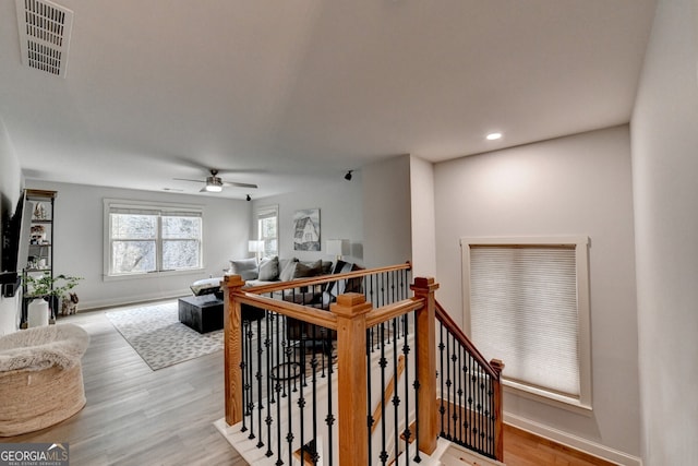 stairway with ceiling fan and hardwood / wood-style flooring