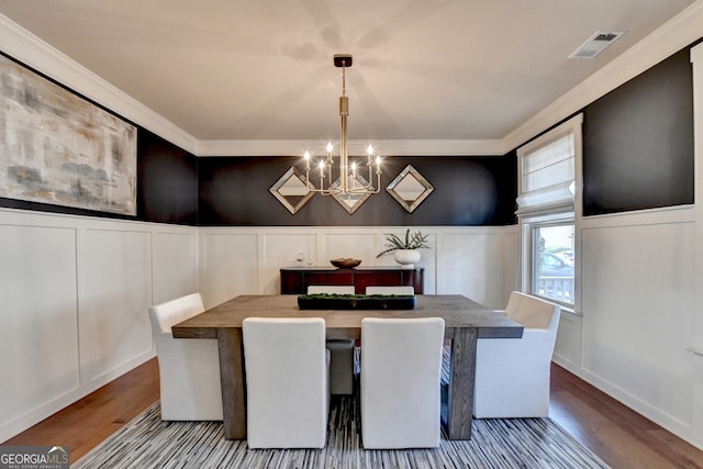 dining space with hardwood / wood-style floors, crown molding, and a chandelier