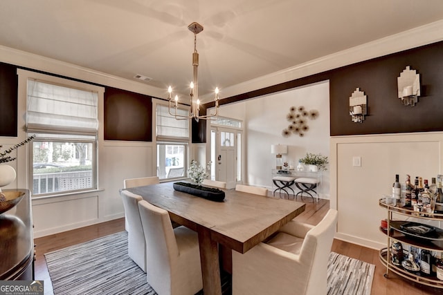 dining room featuring a chandelier, hardwood / wood-style flooring, plenty of natural light, and crown molding