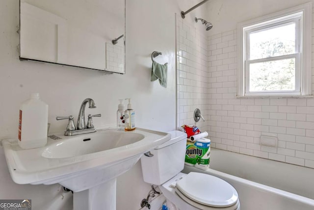 full bathroom featuring tiled shower / bath combo, toilet, and sink