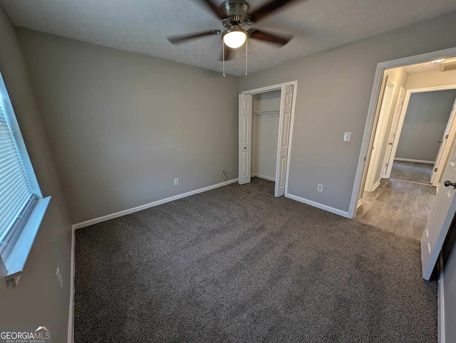 unfurnished bedroom featuring dark colored carpet, a textured ceiling, a closet, and ceiling fan