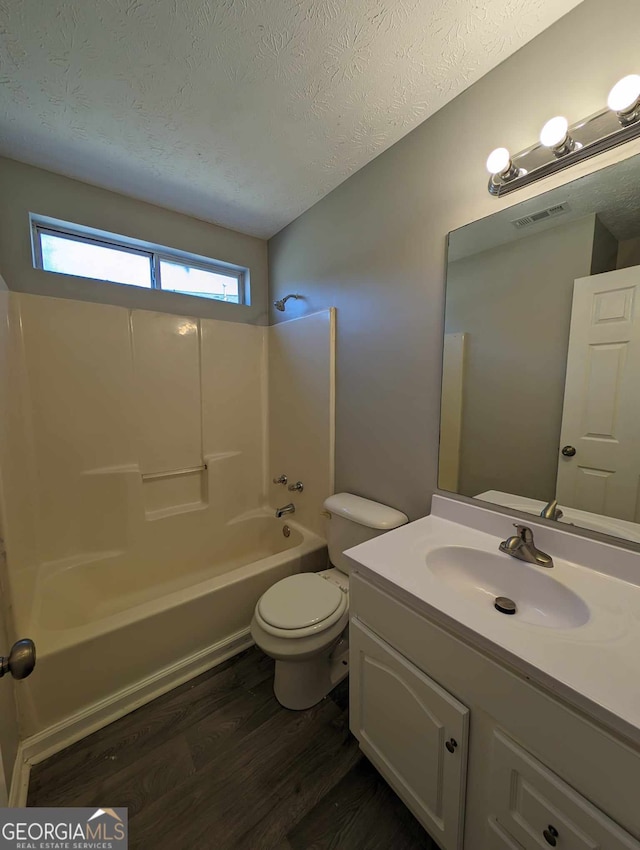 full bathroom featuring a textured ceiling, toilet, vanity, bathtub / shower combination, and hardwood / wood-style flooring