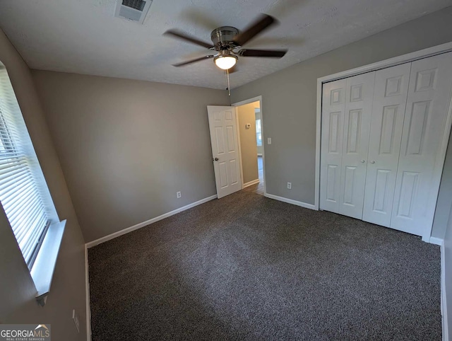 unfurnished bedroom featuring dark colored carpet, ceiling fan, and a closet