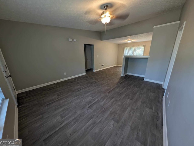 empty room with a textured ceiling, ceiling fan, and dark hardwood / wood-style floors