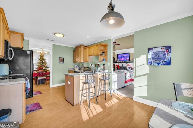 kitchen featuring a kitchen breakfast bar, kitchen peninsula, light hardwood / wood-style flooring, and ornamental molding