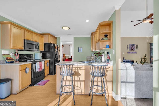 kitchen with a kitchen bar, kitchen peninsula, light wood-type flooring, crown molding, and black appliances