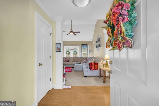 hallway featuring vaulted ceiling, light hardwood / wood-style flooring, and ornamental molding