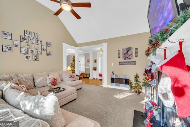 carpeted living room with ceiling fan, high vaulted ceiling, and decorative columns