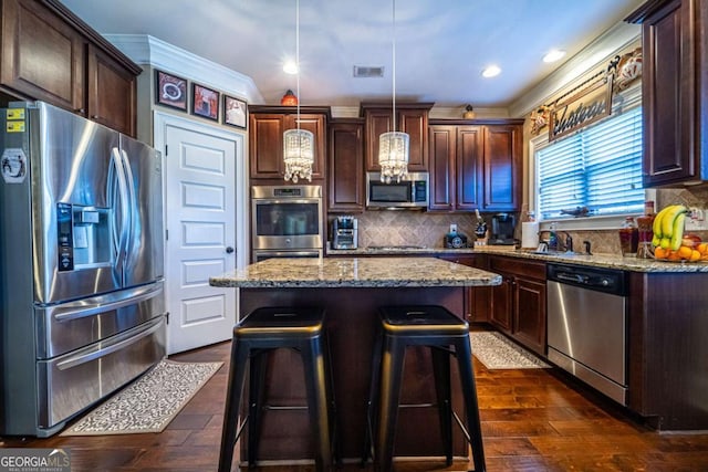 kitchen featuring a center island, an inviting chandelier, ornamental molding, decorative light fixtures, and stainless steel appliances