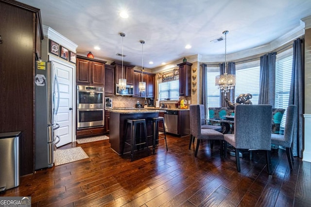 kitchen with stainless steel appliances, dark hardwood / wood-style flooring, a center island, and hanging light fixtures