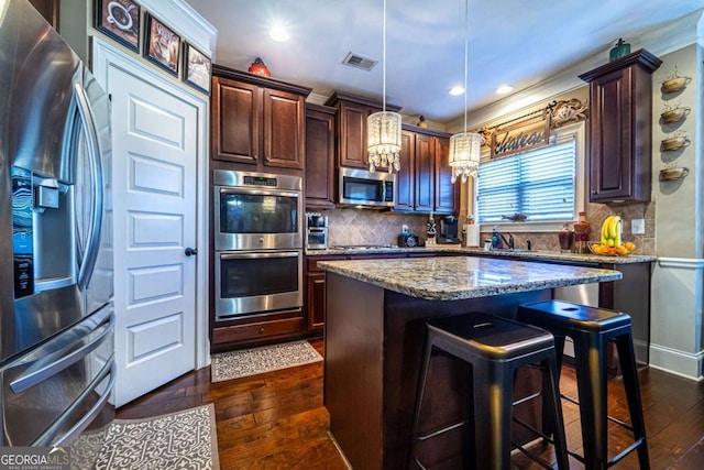 kitchen featuring light stone countertops, appliances with stainless steel finishes, dark hardwood / wood-style floors, and hanging light fixtures