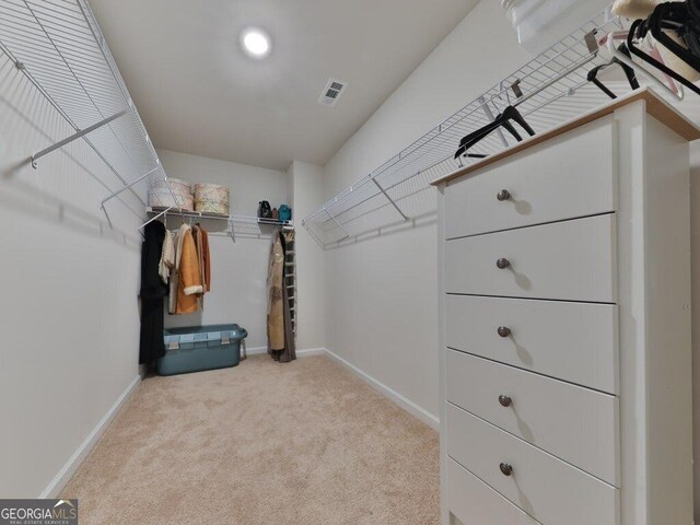 walk in closet featuring light colored carpet