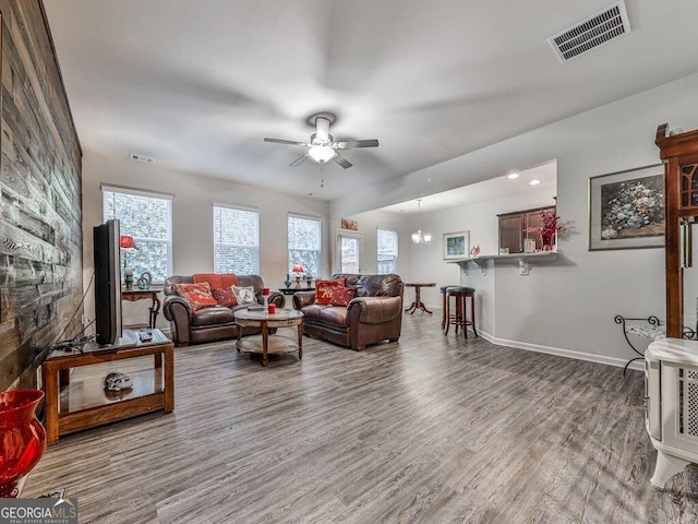 living room with hardwood / wood-style floors and ceiling fan with notable chandelier