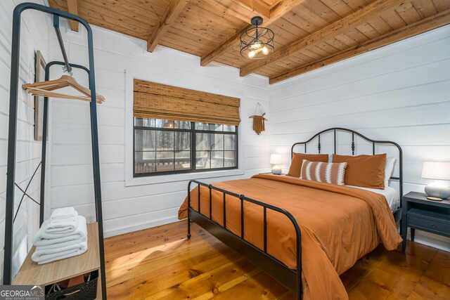 bedroom with wood walls, beamed ceiling, wooden ceiling, and wood-type flooring