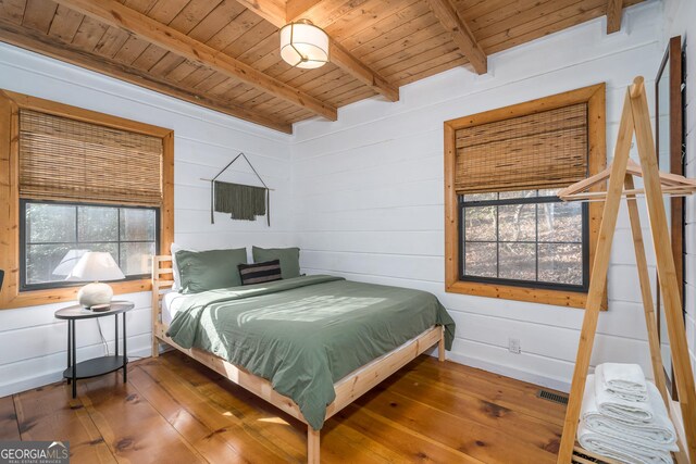 bedroom featuring beamed ceiling, wood walls, wood ceiling, and hardwood / wood-style floors